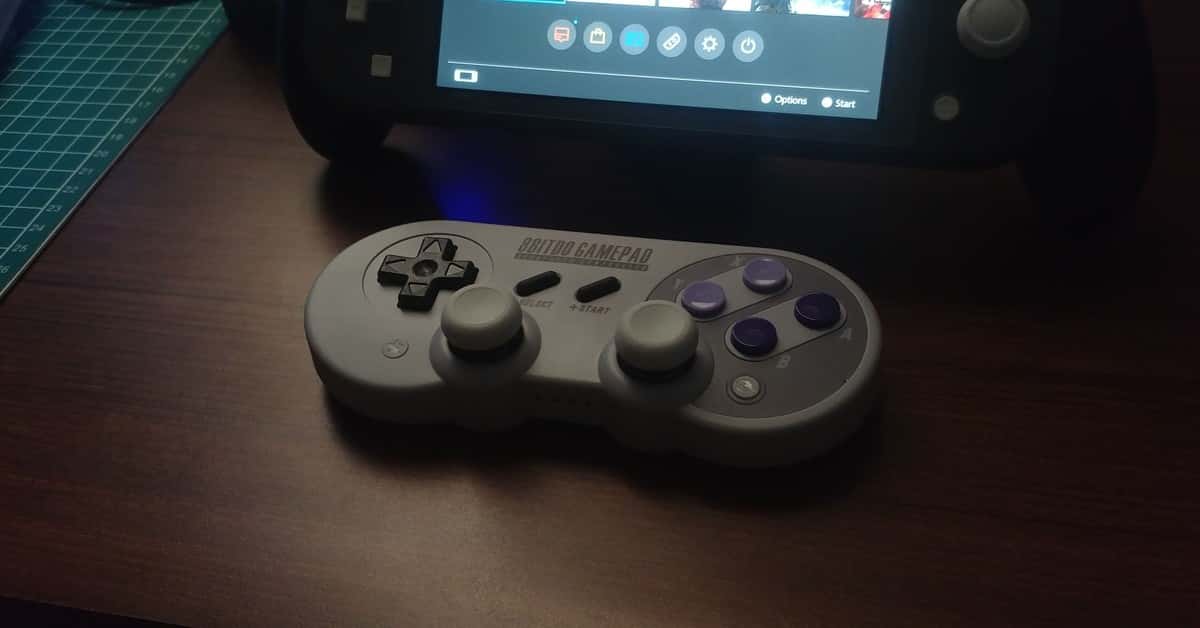 Close-up of a retro-style game controller alongside a modern handheld console on a wooden table.