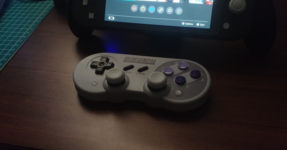 Close-up of a retro-style game controller alongside a modern handheld console on a wooden table.