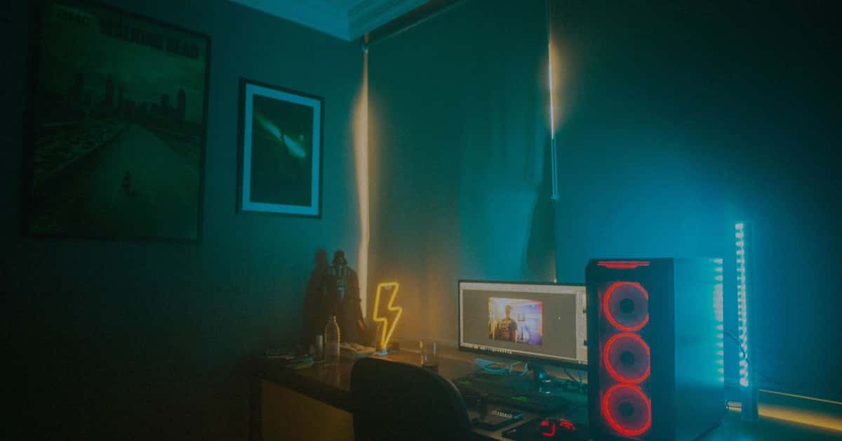 A dimly lit minimalist gaming setup featuring a desktop PC and neon lights.