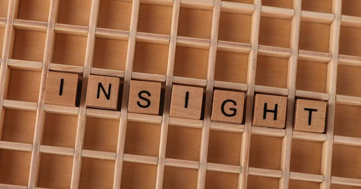 Wooden Scrabble letters spelling 'INSIGHT' on a wooden grid creating a conceptual image.