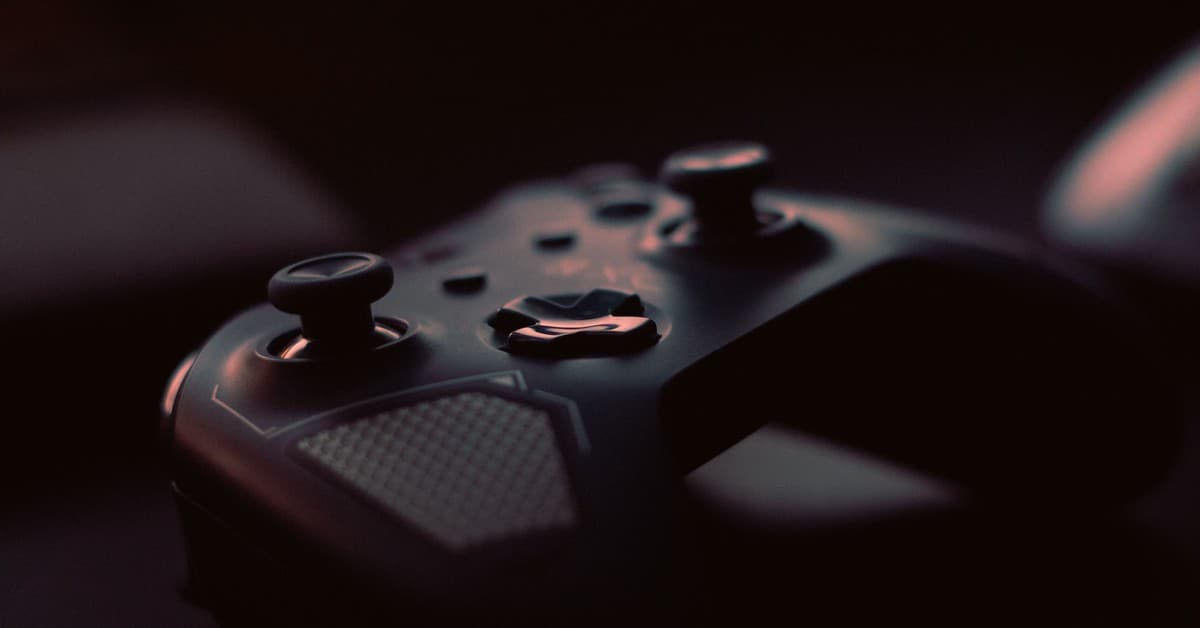 A close-up shot of a game controller in low light, highlighting its design and buttons.