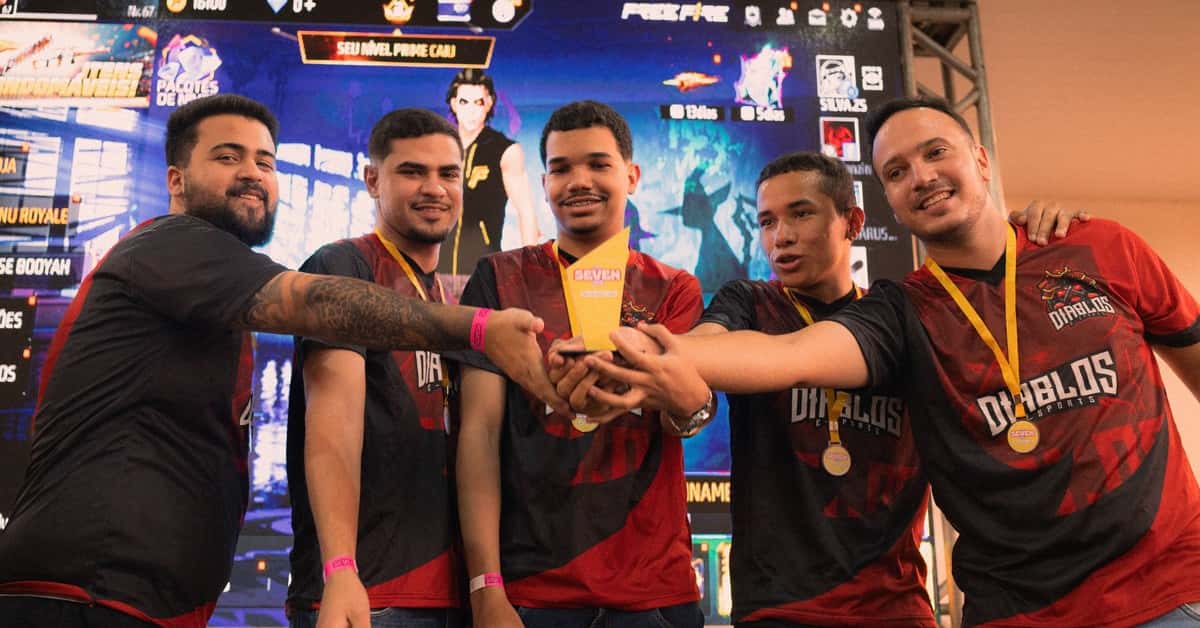 A group of gamers celebrating their victory at an e-sports event holding a trophy.