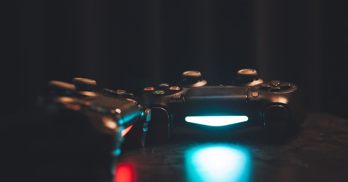 Close-up of glowing gaming controllers on a dark surface, creating a moody ambiance.