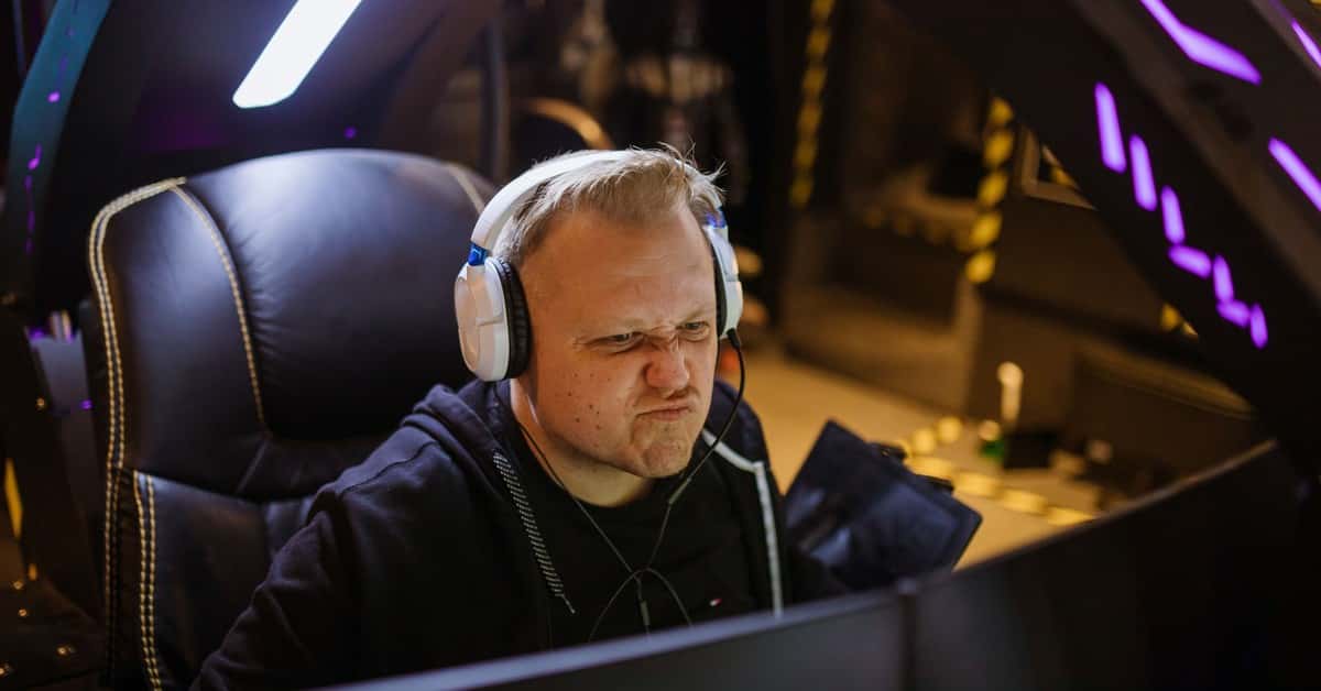 Focused gamer wearing headphones intensely playing an online esports game indoors.