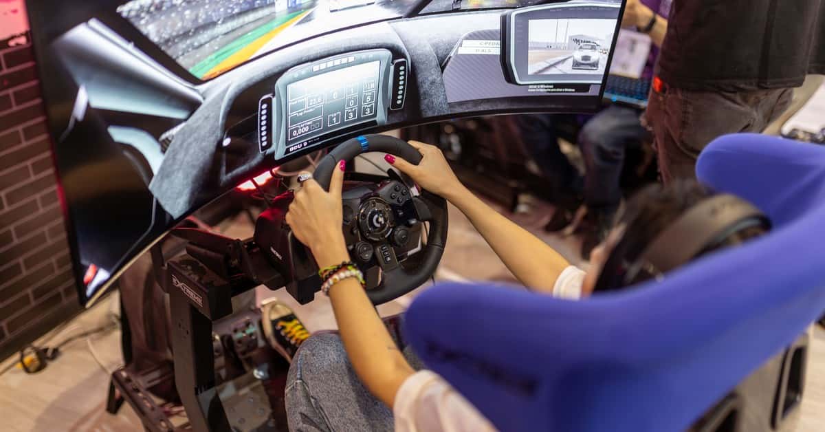 Person using a realistic VR racing simulator at a gaming event, focused on the immersive experience.