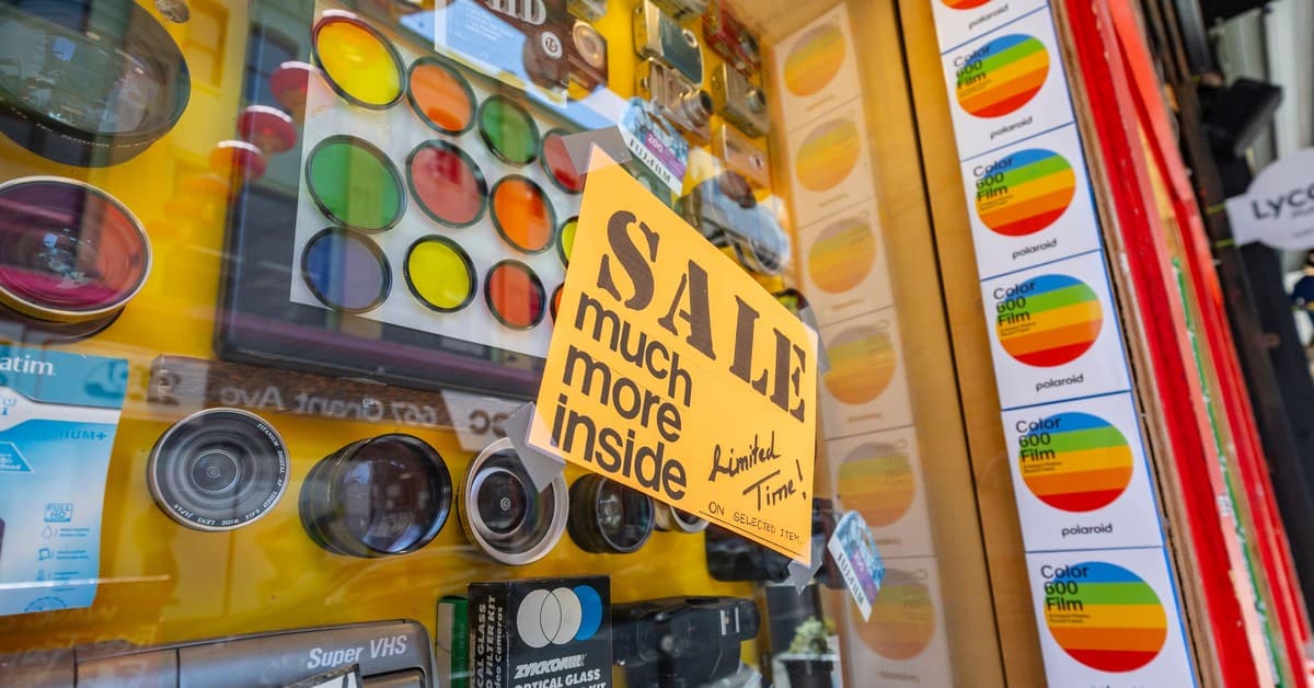 Vibrant display of camera lenses and accessories with a sale sign in a shop window.