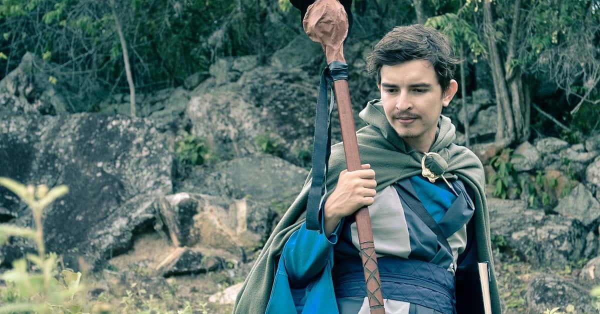 Man wearing medieval cosplay costume holding staff in a forest setting in Colombia.