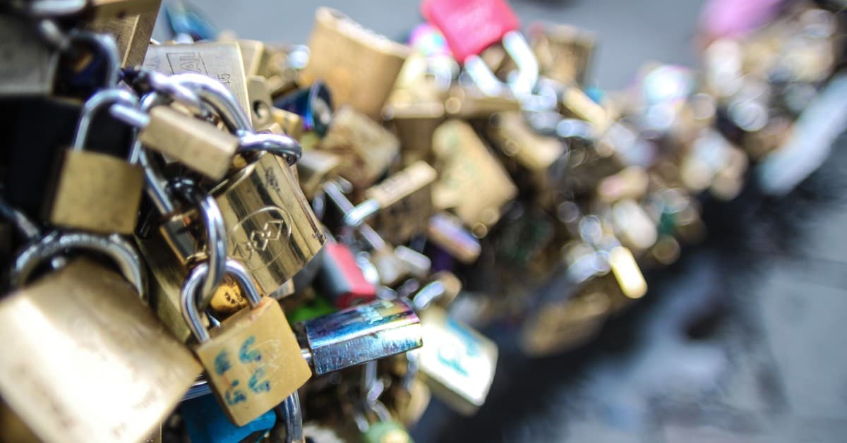 A close-up of multicolored love padlocks symbolizing love and commitment on a bridge railing.