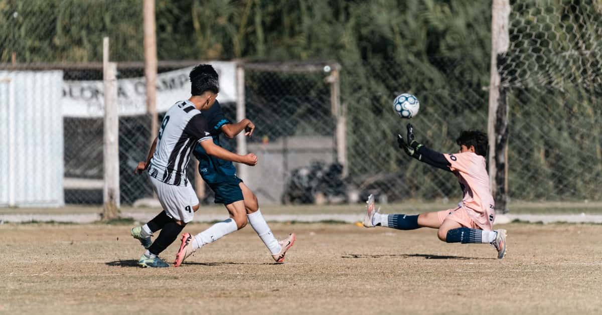 Football match action shot capturing a goalkeeper's dramatic save during a game.