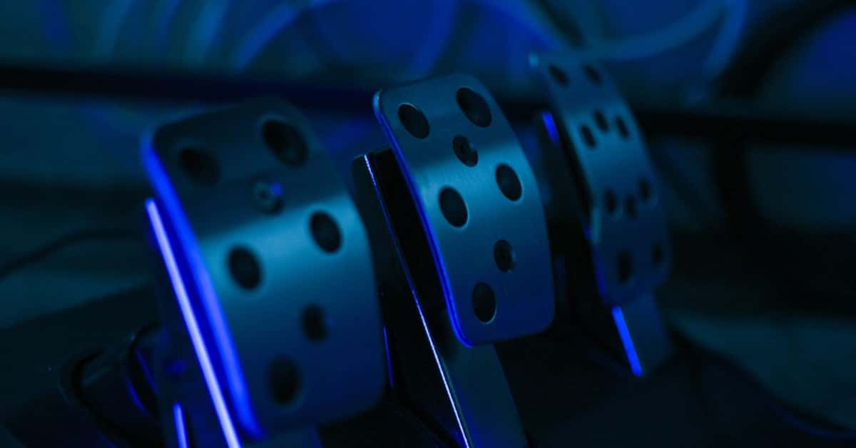 Detailed shot of gaming pedals illuminated by blue light, perfect for racing simulation setups.