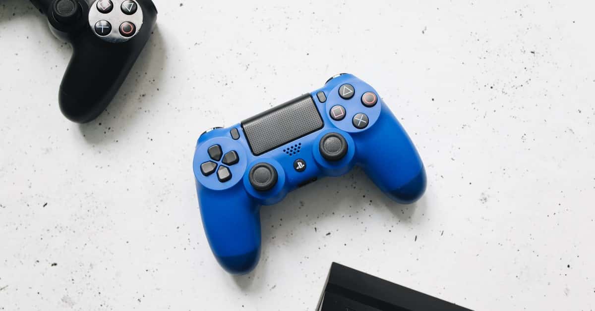A close-up view of black and blue game controllers on a white speckled surface.