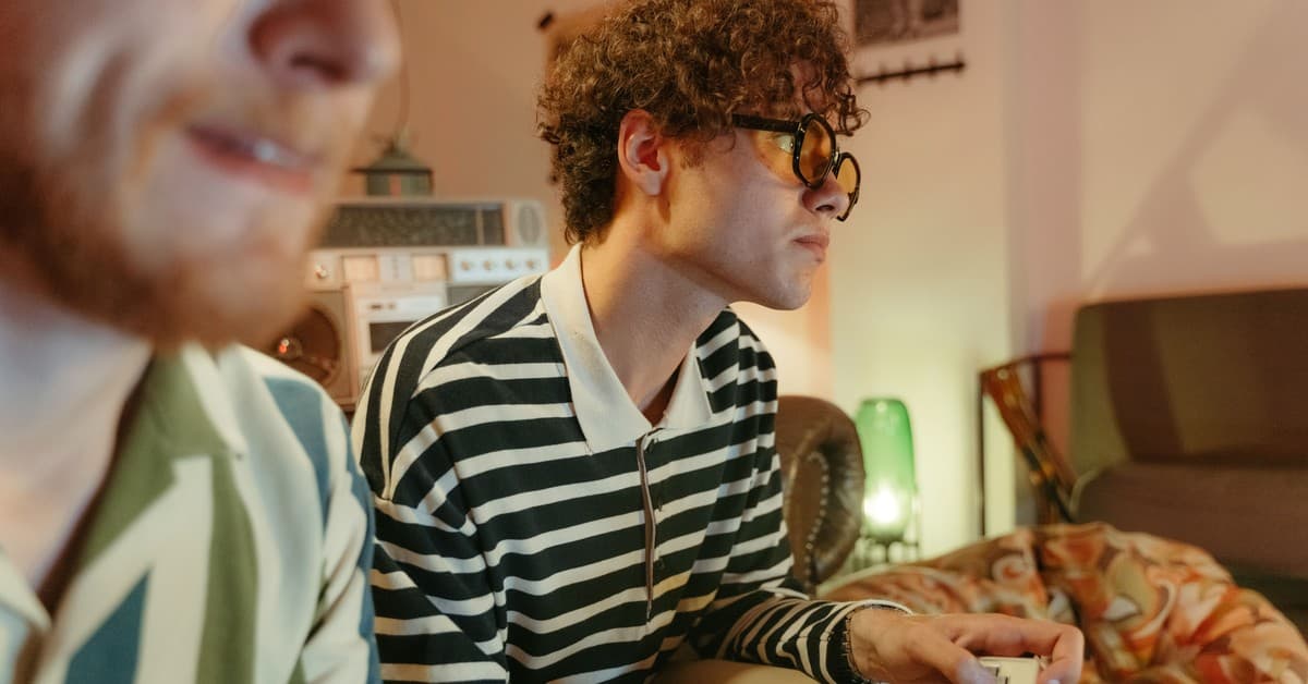 Two young men enjoying video games in a retro-themed room, capturing a nostalgic and fun atmosphere.