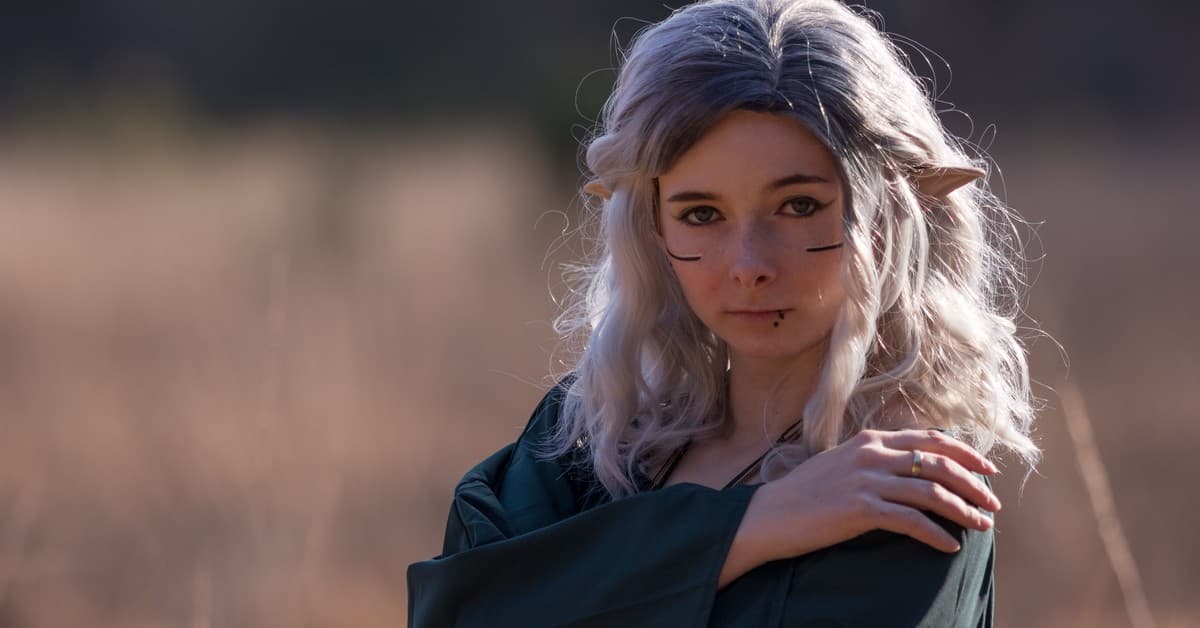 A captivating elf cosplay portrait outdoors with fantasy makeup and ears.