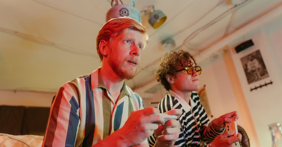 Two men playing video games with controllers and having fun in a cozy room.