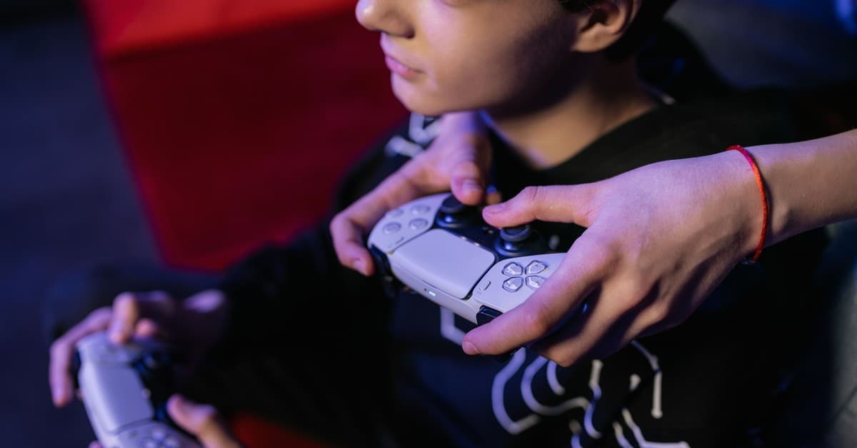 Close-up of teenagers playing video games together using modern game controllers.
