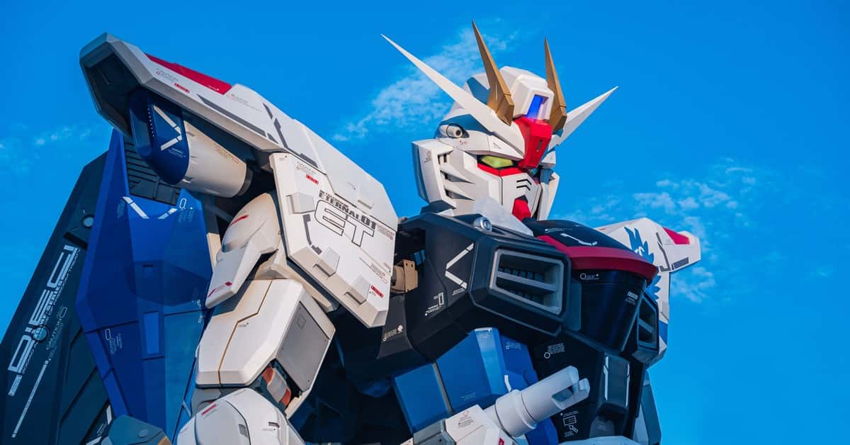 Close-up of a giant Gundam robot statue set against a clear blue sky.