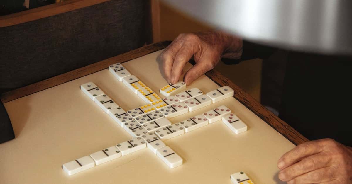 Elderly hands engaged in a domino game on a table in Brazil, capturing leisure moments and social interaction.