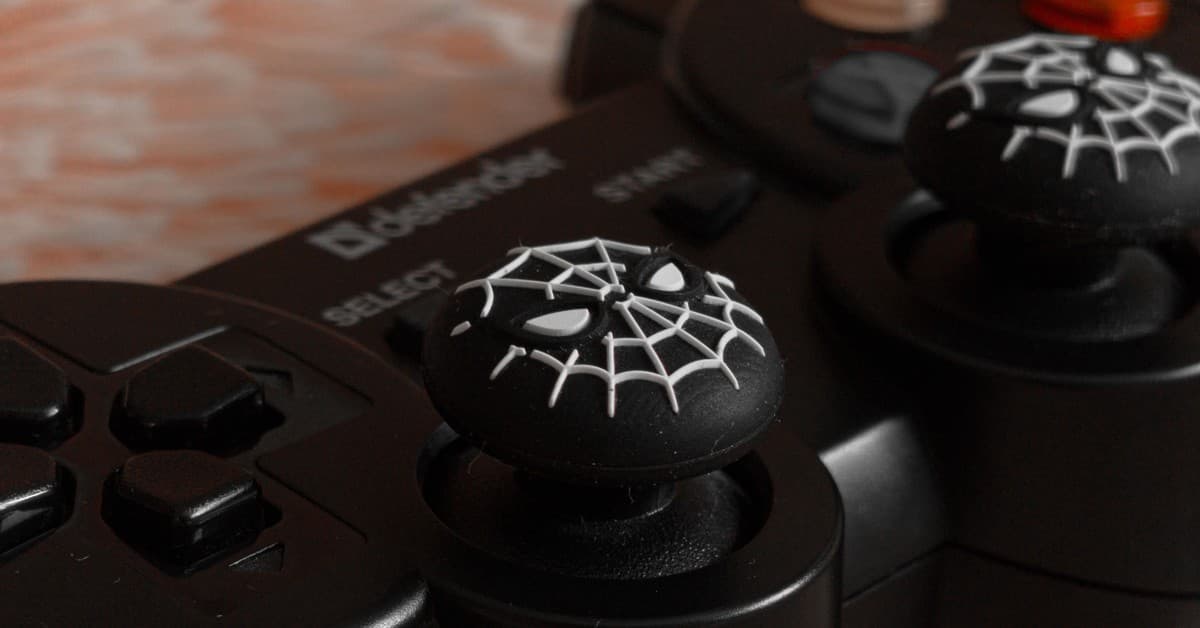 Close-up of a black gaming controller featuring a spider web design on the joysticks for entertainment enthusiasts.