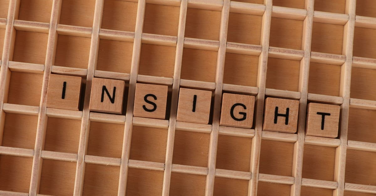 Wooden Scrabble letters spelling 'INSIGHT' on a wooden grid creating a conceptual image.