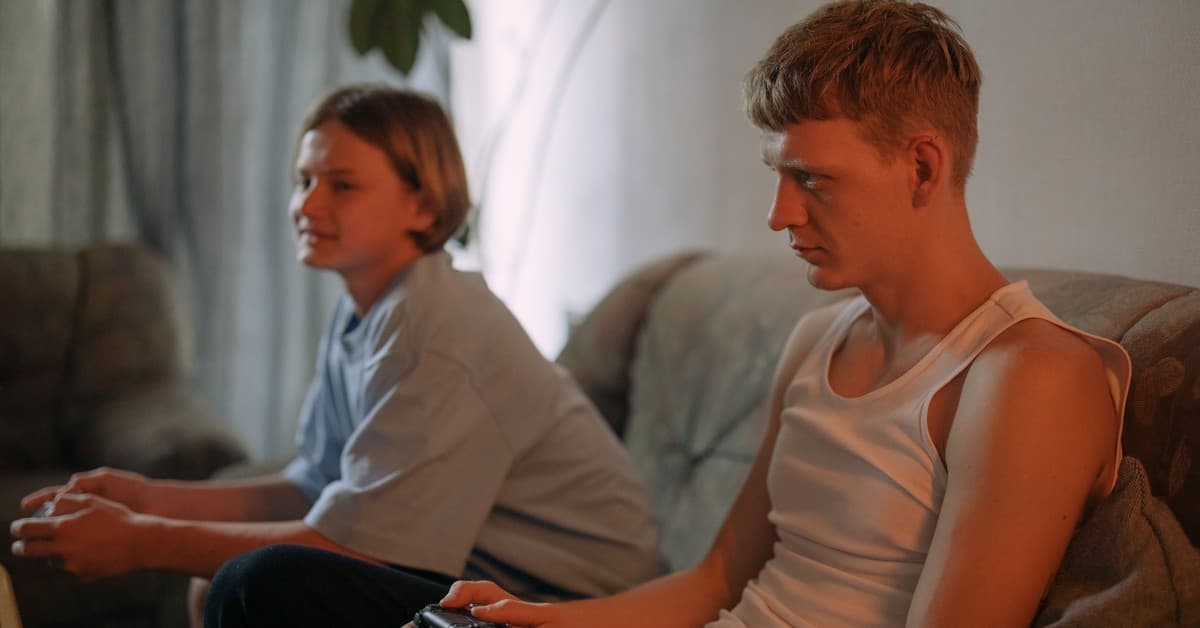 Two young men focused on gaming together in a cozy living room.
