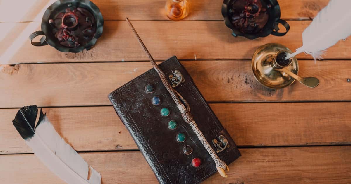 A collection of wizarding items including a wand, spell book, and quill on a rustic wooden table.
