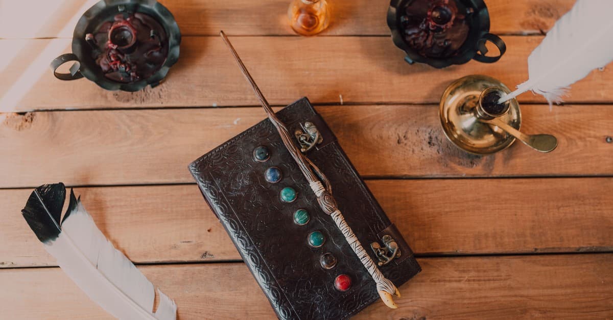 A collection of wizarding items including a wand, spell book, and quill on a rustic wooden table.