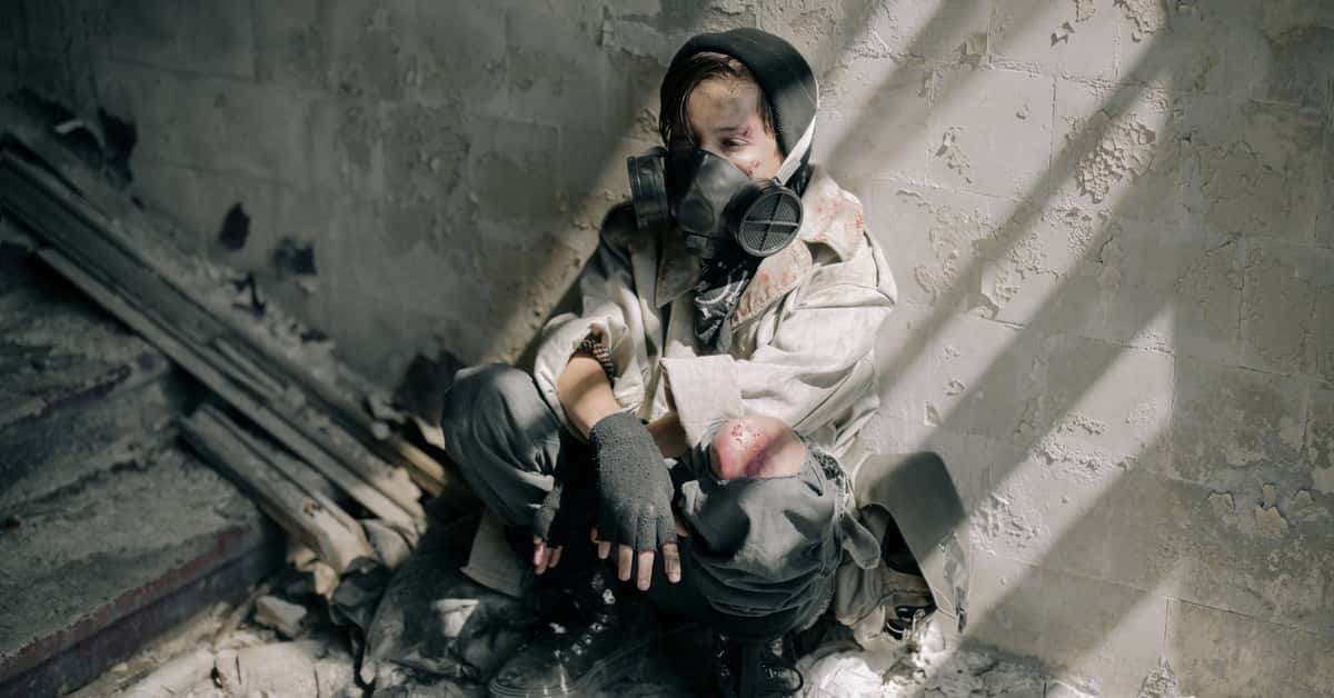 A young person in a gas mask sits in a decaying, abandoned building, evoking themes of survival and desolation.