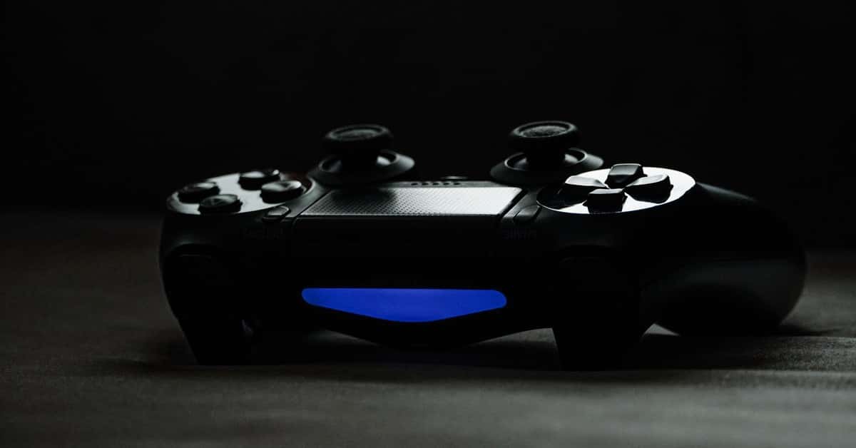 Black gaming controller with glowing blue light on a dark surface, perfect for tech-themed projects.
