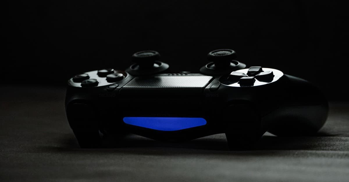 Black gaming controller with glowing blue light on a dark surface, perfect for tech-themed projects.