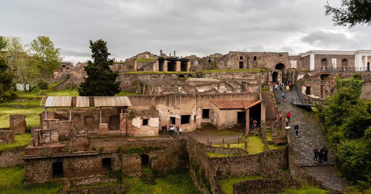 Explore ancient ruins of Pompeii under cloudy skies, capturing rich historical details and lush greenery.