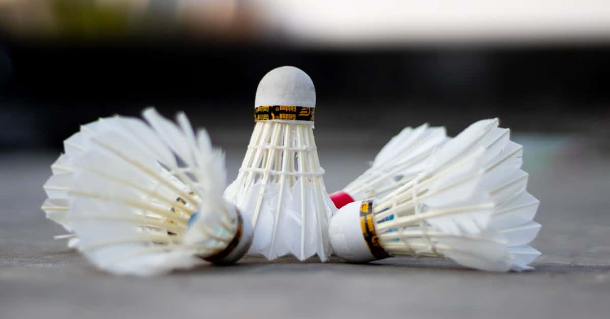 Detailed view of three badminton shuttlecocks laying on a court surface.