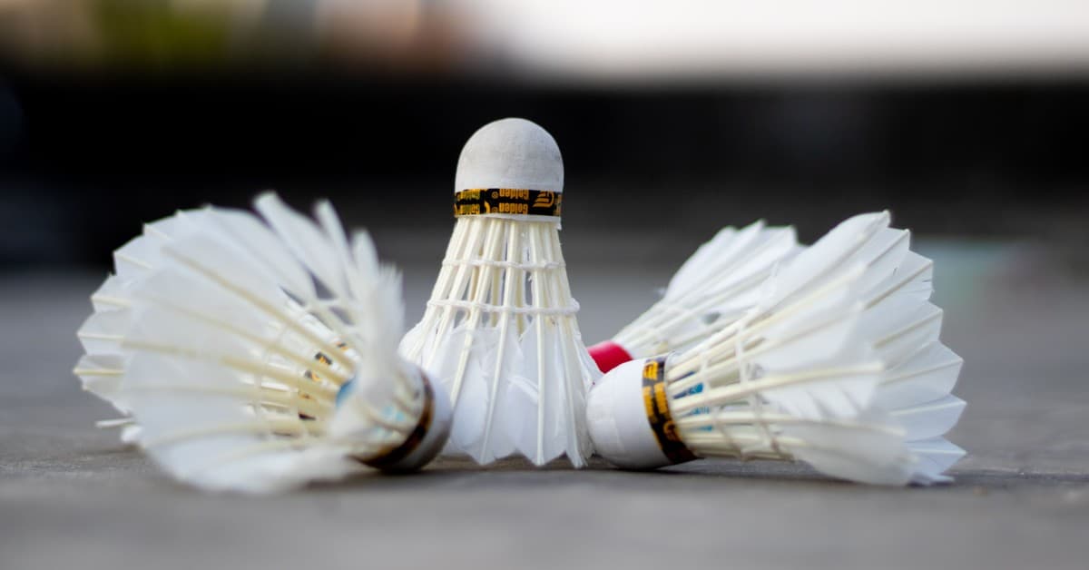 Detailed view of three badminton shuttlecocks laying on a court surface.