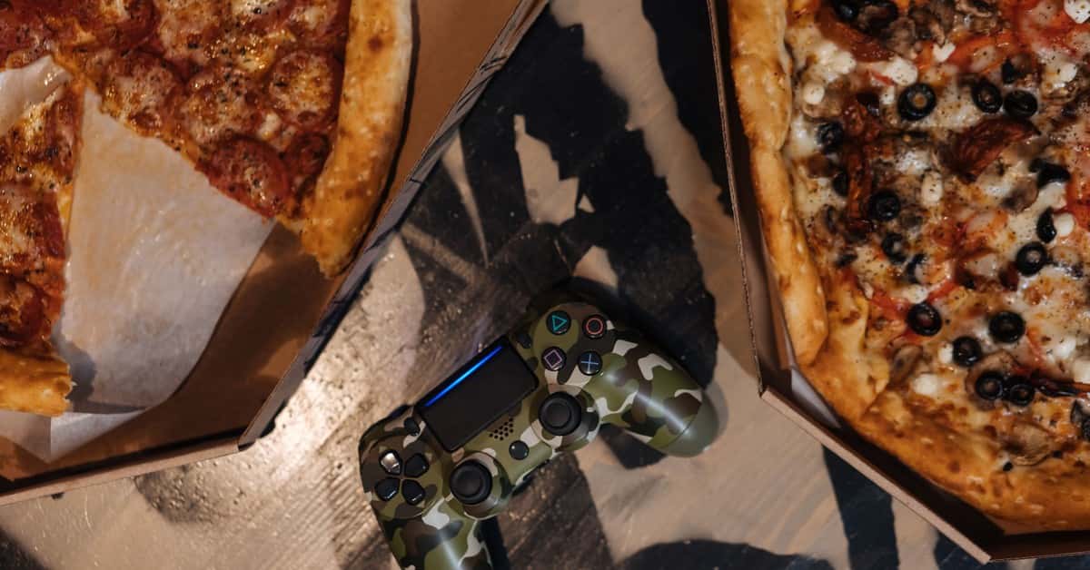 Overhead view of pizzas next to a gaming controller, perfect for leisure time.