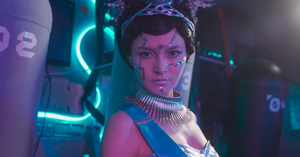 A woman with sci-fi makeup and armor in a vibrant, neon-lit environment.